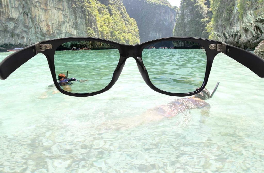 sunglasses partially filtering a view of scuba divers in water with heavy glare
